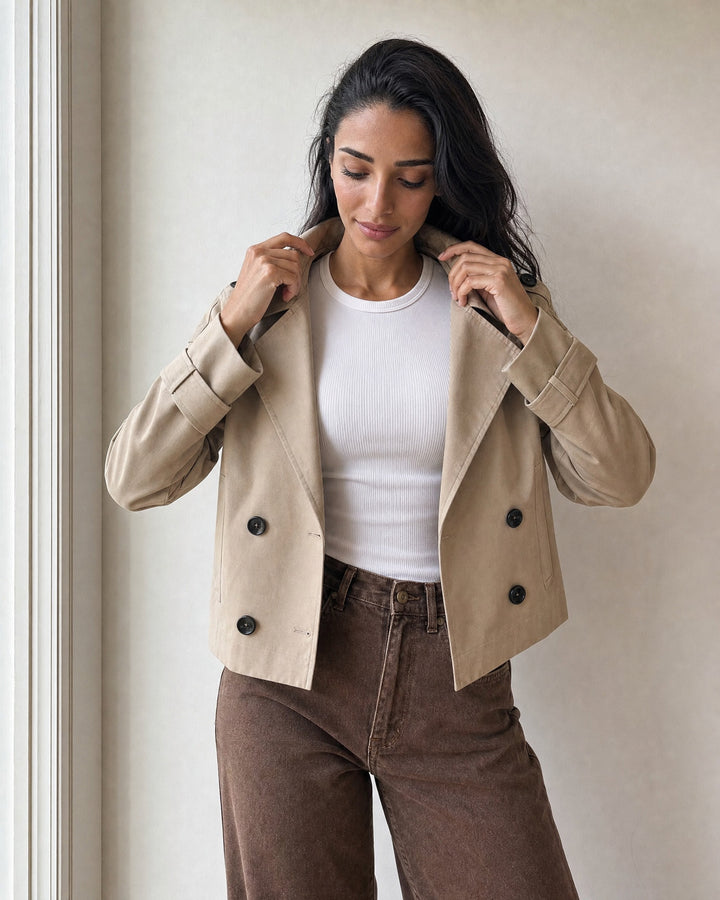 settling the collar of the beige cropped trench coat