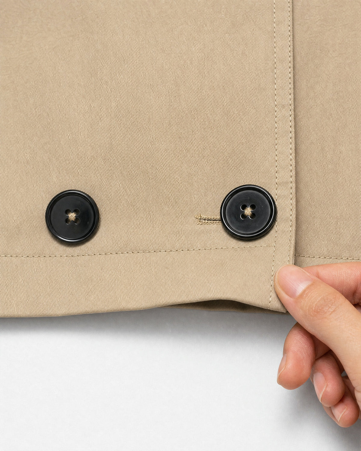 close-up of the front buttons and fabric of the beige cropped trench coat